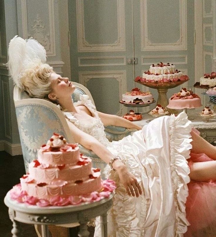 This may contain: a woman laying on a chair next to a table full of cakes