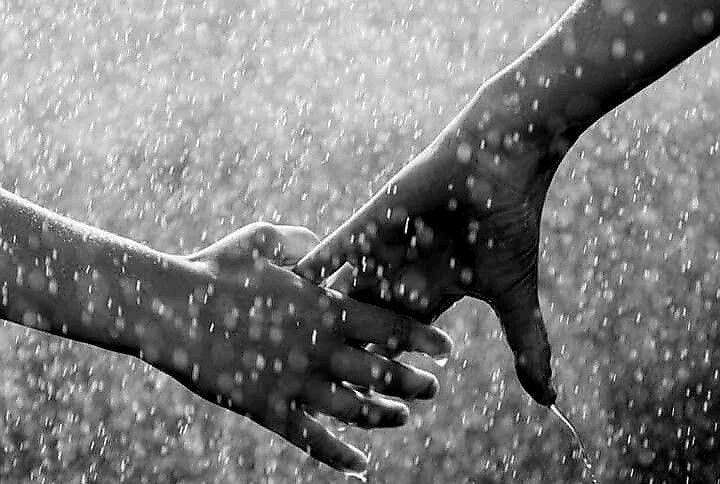 Two hands holding each other in the rain