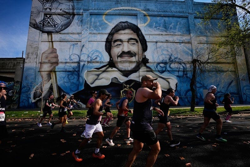 Runners pass a mural of Diego Maradona during the Buenos Aires Marathon in Argentina, Sunday, Sept. 20, 2026. (AP Photo/Natacha Pisarenko)