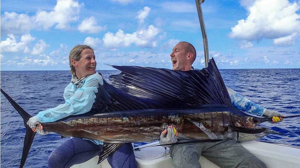 Female Angler Holding tail of Sailfish looking at Angler holding Bill