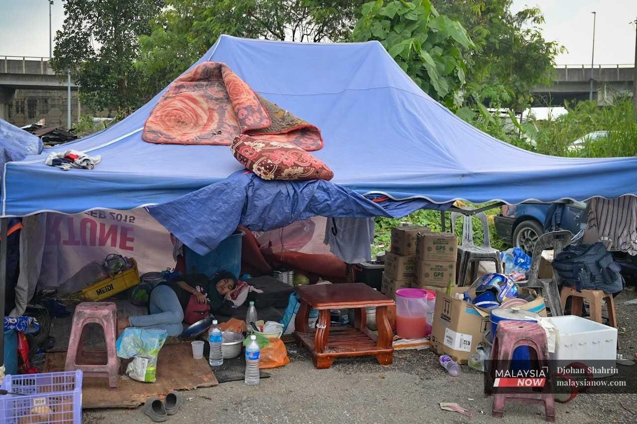 A resident of Kampung Sri Makmur takes a nap under a tent surrounded by the belongings she saved after her house was demolished by authorities on May 27, 2024. A resident of Kampung Sri Makmur takes a nap under a tent surrounded by the belongings she saved after her house was demolished by authorities on May 27, 2024.