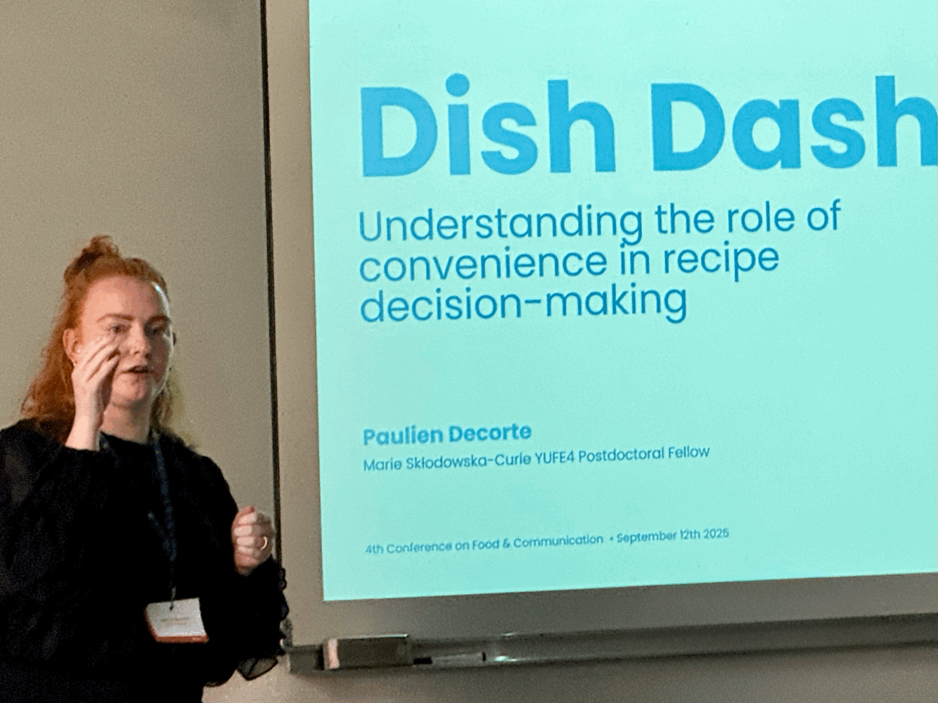 Woman next to a projected slide with title: Dish Dash: Understanding the role of convenience in recipe decision-making.