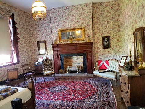 The Dickson Williams Mansion, a brick building with a white porch; the parlor, showing a round table surrounded by black chairs on a red oriental rug in front of a fireplace; the kitchen area, showing original north carolina furniture; bedrooms of the house, along with a portrait of General John Hunt Morgan sitting in a chair in a black coat with tall black boots; and the bed where he spent his last night.