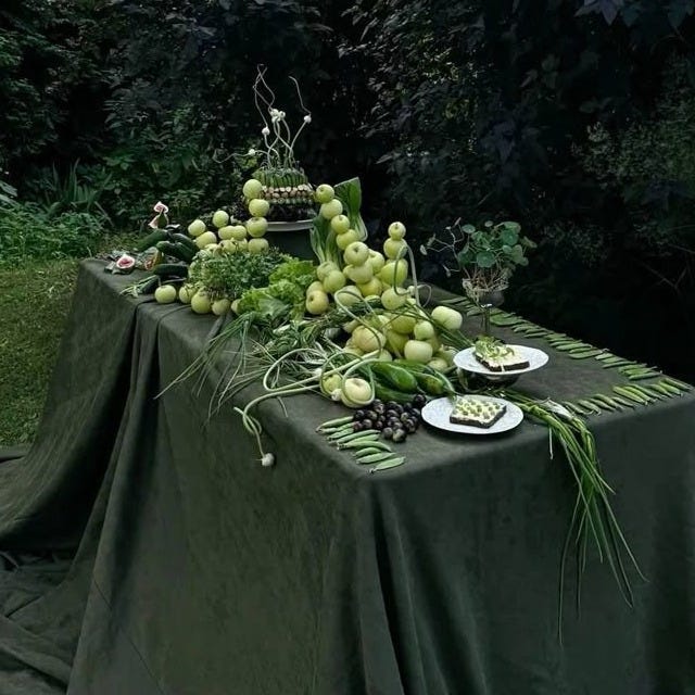This may contain: a table covered with grapes and other fruit on it's side in front of some bushes