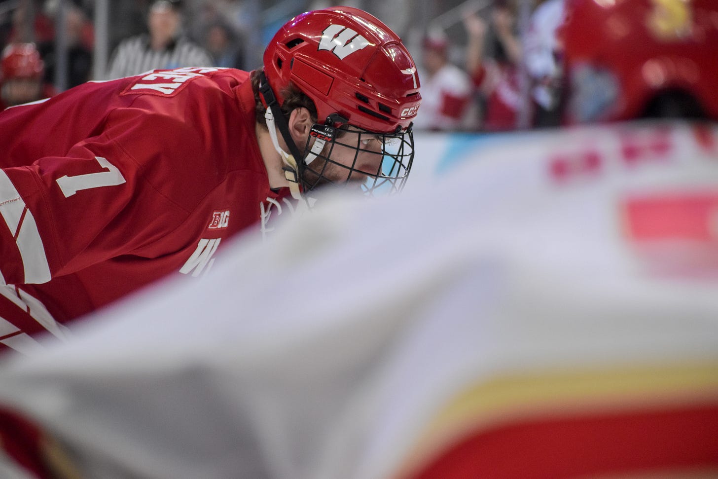 Wisconsin Badgers Gavin Morrissey in face off circle behind player. Big Ten Conference logo on right shoulder.