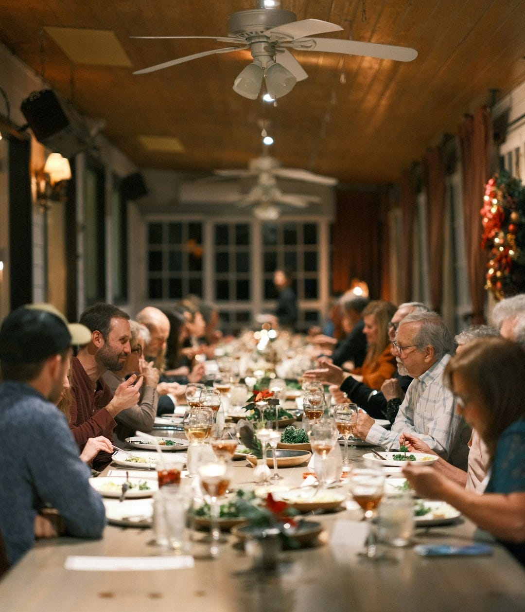 A gathering of friends celebrating Christmas while sitting at a table in a restaurant.