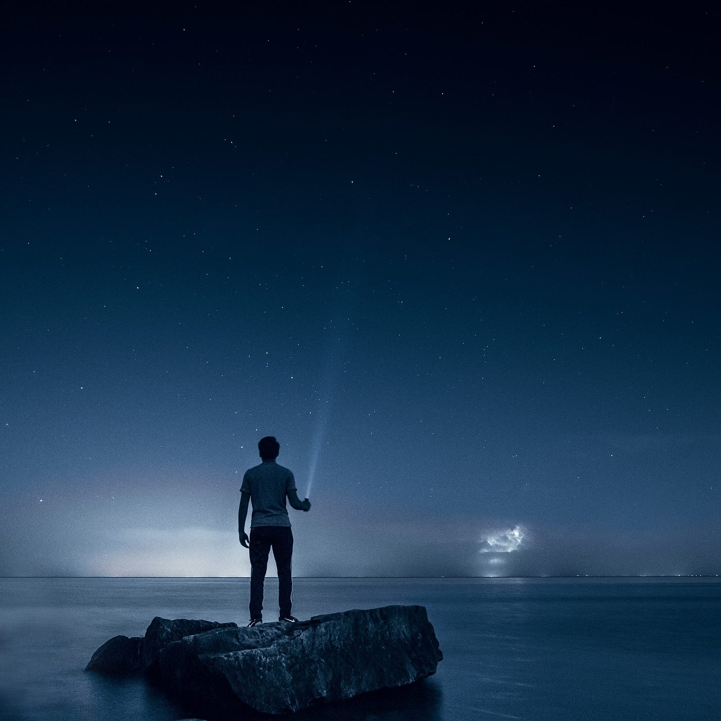 Man holding flashlight standing on rock Man holding flashlight standing on rock