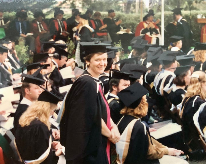 A woman in a cap and gown and a small girl in a mortar board
