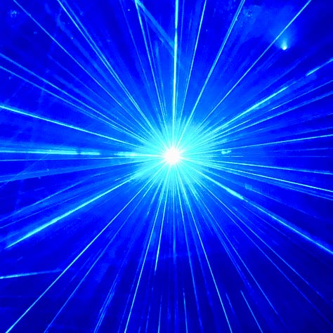 A blue and violet laser light beams through the dark forest. All around, sapphire faerie lights shine starbursts into the night