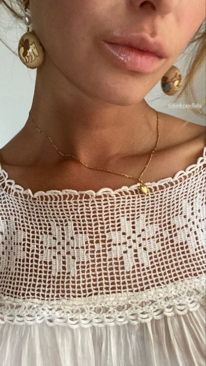 This may contain: a close up of a woman wearing a white dress and gold earrings on her neck