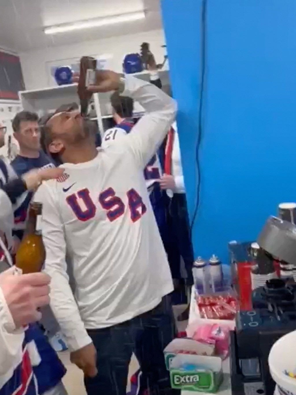 Kash Patel drinks a beer ion front of hockey players.