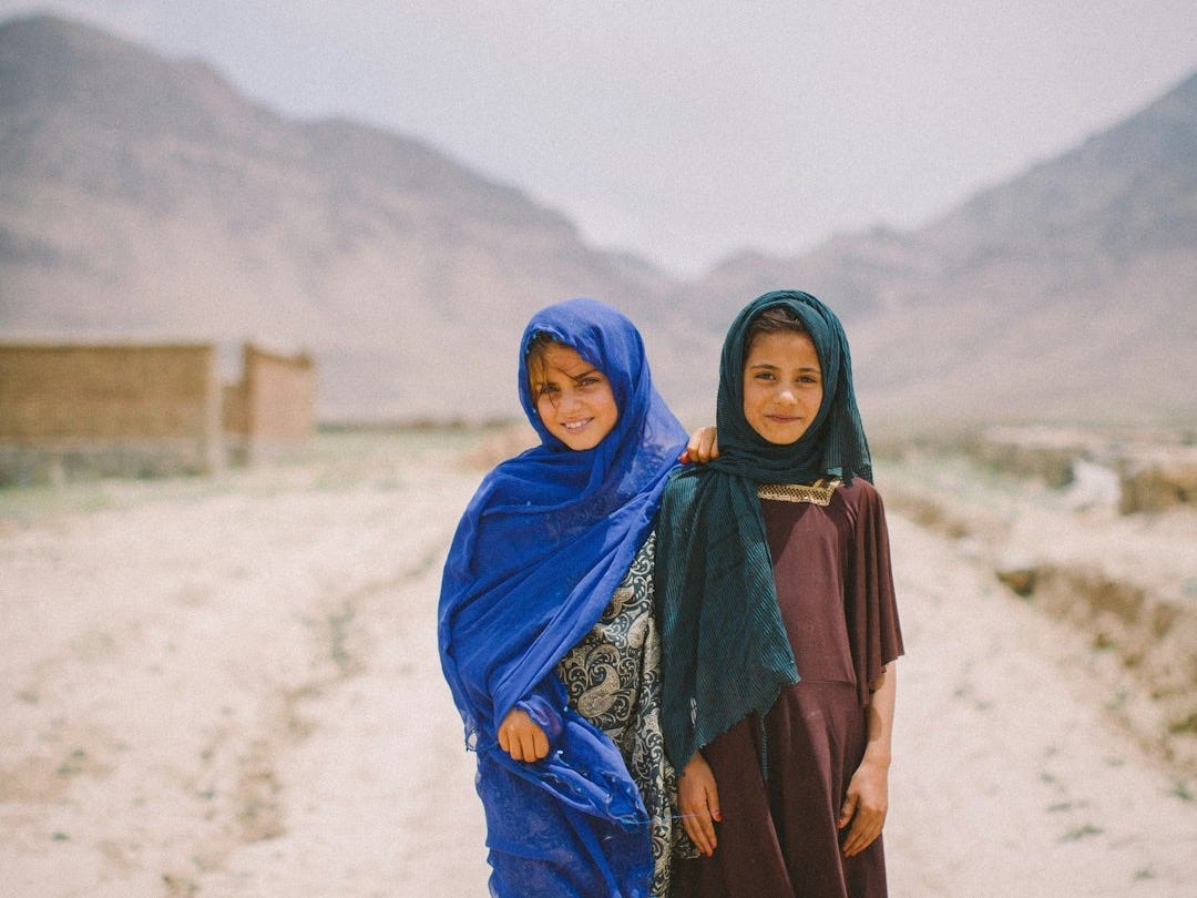 Two women standing in the middle of a dirt road