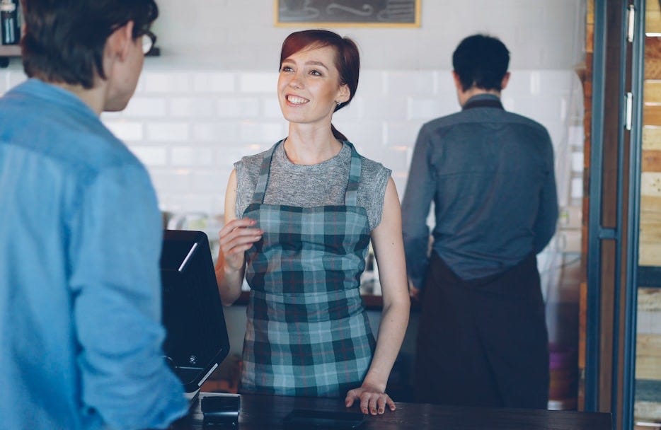 A barista is talking to a customer. A barista is talking to a customer.