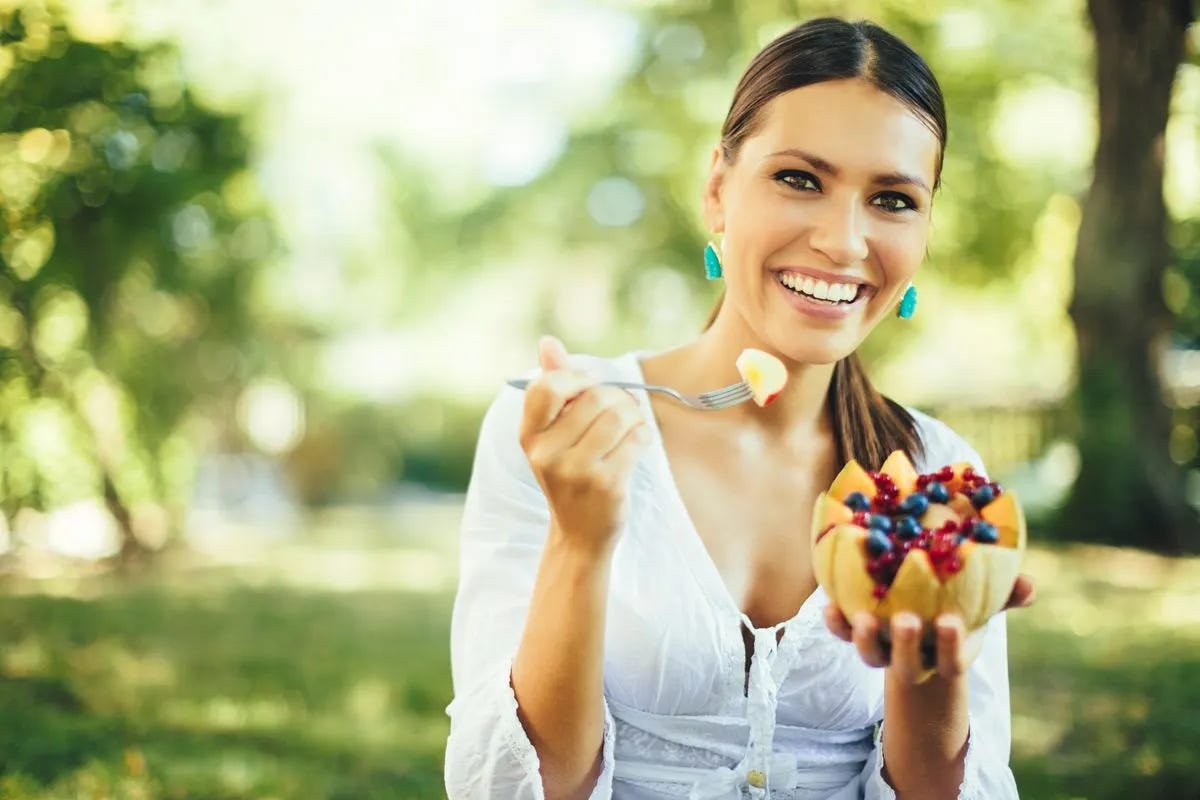 Smiling woman holding a fruit salad in a cantaloupe shell. Smiling woman holding a fruit salad in a cantaloupe shell.