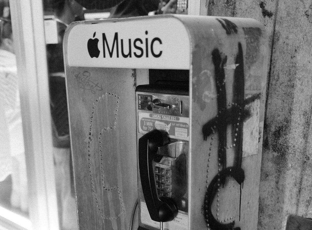 A payphone booth with apple music text and graffiti. A payphone booth with apple music text and graffiti.
