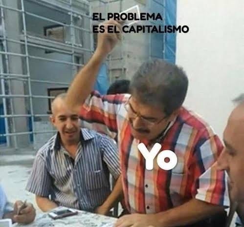 Roda de baralho com homens de meia idade. Um está em pé, com um jogo de cartas na mão, pronto para lançar à mesa. Perto da mão levantada está escrito: "O problema é o capitalismo". No peito dele está escrito: "eu". Roda de baralho com homens de meia idade. Um está em pé, com um jogo de cartas na mão, pronto para lançar à mesa. Perto da mão levantada está escrito: "O problema é o capitalismo". No peito dele está escrito: "eu".