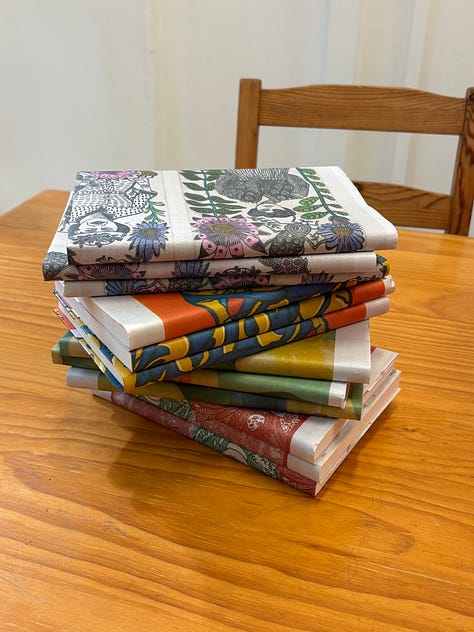 A stack of wrapped books, a promotion for the 'At Our Mothers' Table' reading event on 2 August, and the front of the Pink Shorts Press shop in Adelaide Arcade.