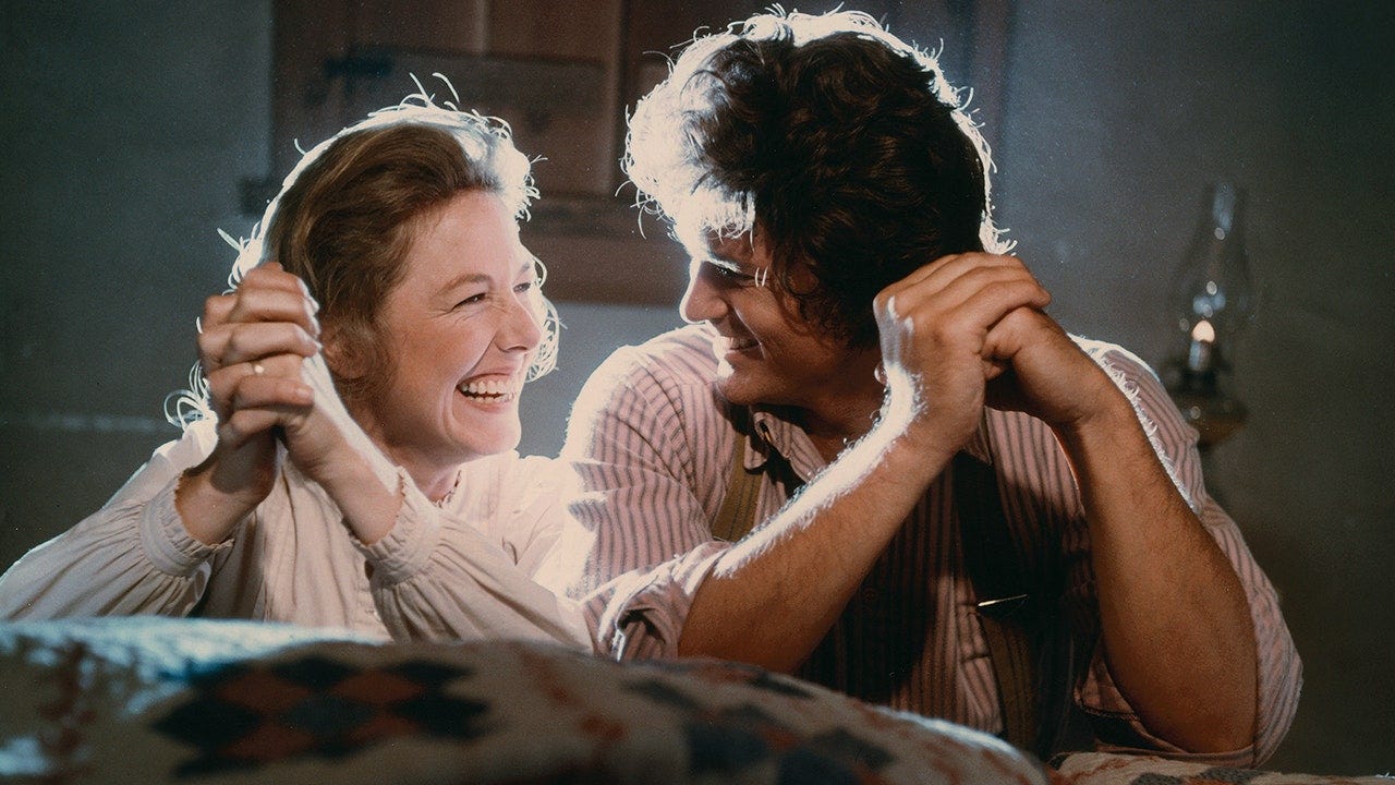 Screenshot from the TV show Little House on the Prairie featuring Karen Grassle and Michael Landon as Caroline and Charles Ingalls while they pray, smiling and laughing at each other.