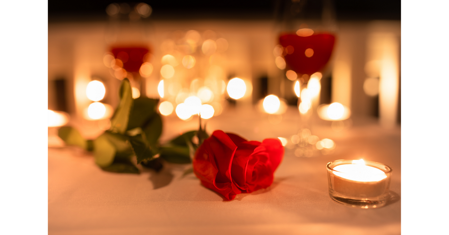 Romantic table centerpiece featuring a red rose, candlelight and wine glasses for an intimate book club evening.