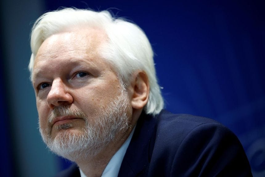 Julian Assange is seen against a dark blue backdrop.