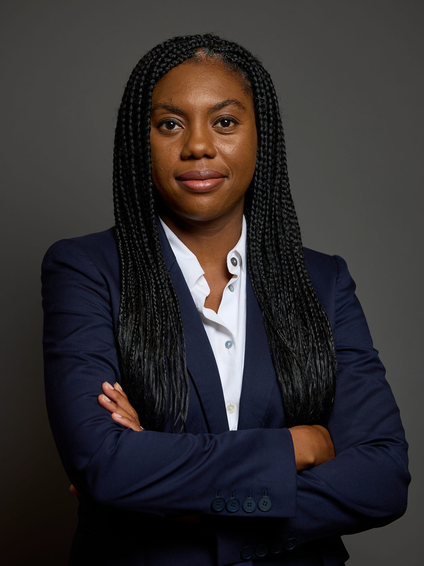 Kemi Badenoch stands with her arms folded across her chest.