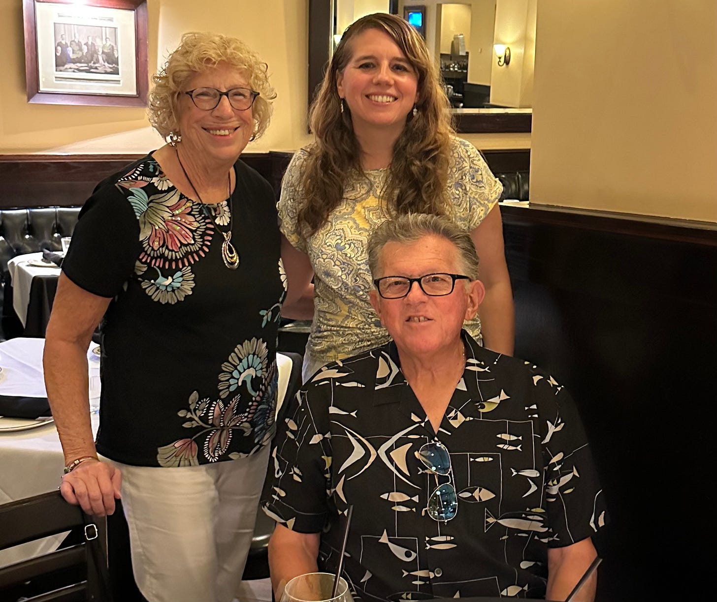 Three people smiling for the camera in a restaurant.