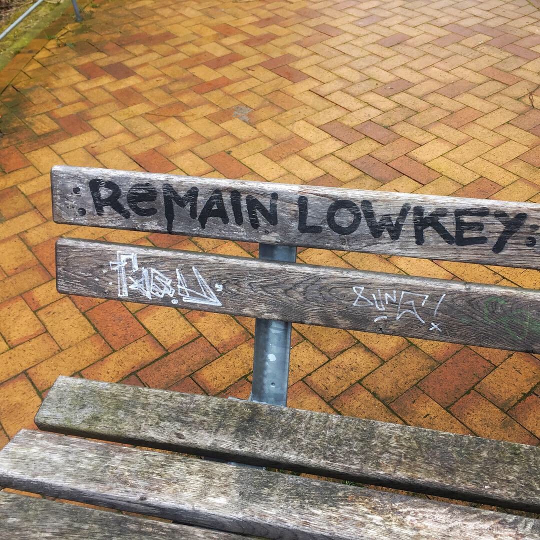 A bench with graffiti reading "remain lowkey"
