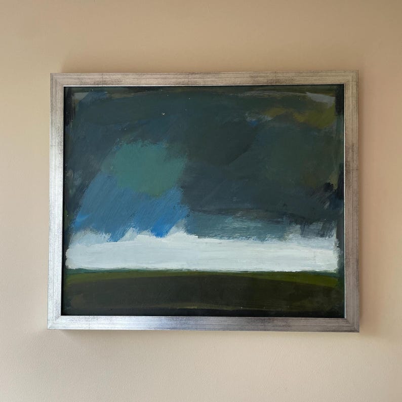 May include: Abstract landscape painting in a silver frame. The artwork features a dark blue and green sky with a white horizontal band and a dark green base. The painting has a textured, brushstroke appearance.
