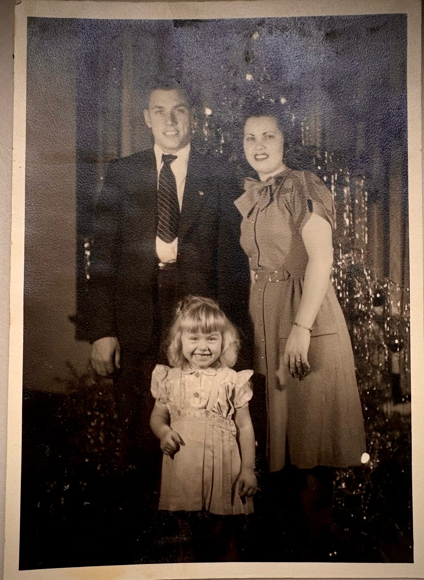 parents and a blonde child in front of christmas tree circa 1947