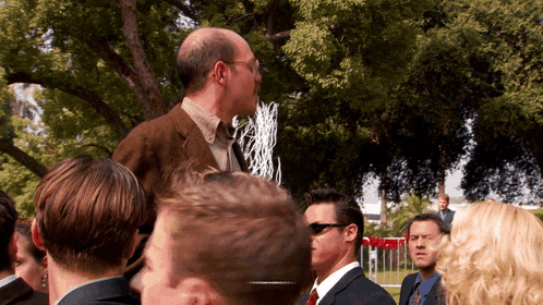 a man in a suit and tie stands in a crowd