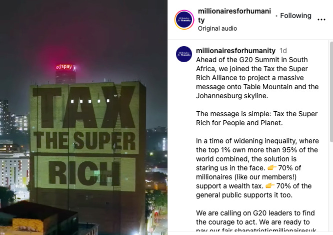A photo of a building with the words "Tax the Super Rich" projected on the side of it. With the instagram post text to the right of the photo from the group Millionaires for Humanity.