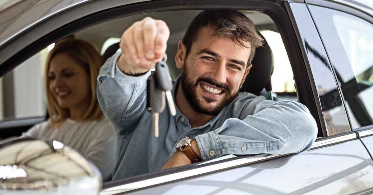 Young man holding car key from new car
