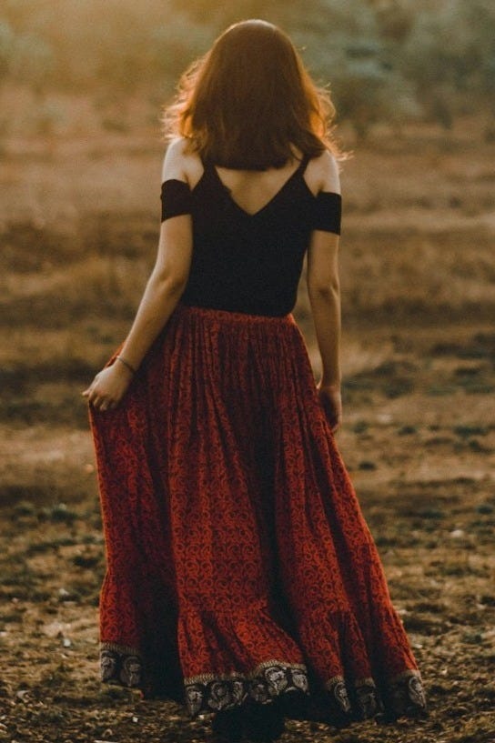 woman in black and red dress standing on dirt ground during daytime woman in black and red dress standing on dirt ground during daytime