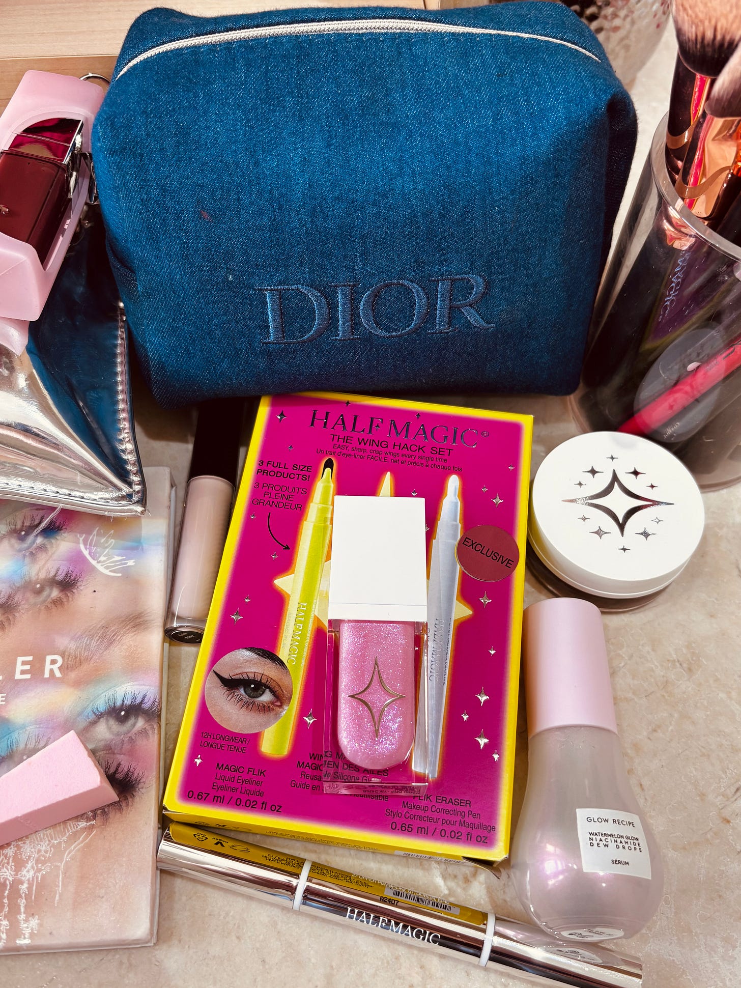 A beauty editor's vanity featuring the Half Magic Wing Hack Set, Glow Recipe Dew Drops, and a Dior denim makeup bag. A beauty editor's vanity featuring the Half Magic Wing Hack Set, Glow Recipe Dew Drops, and a Dior denim makeup bag.