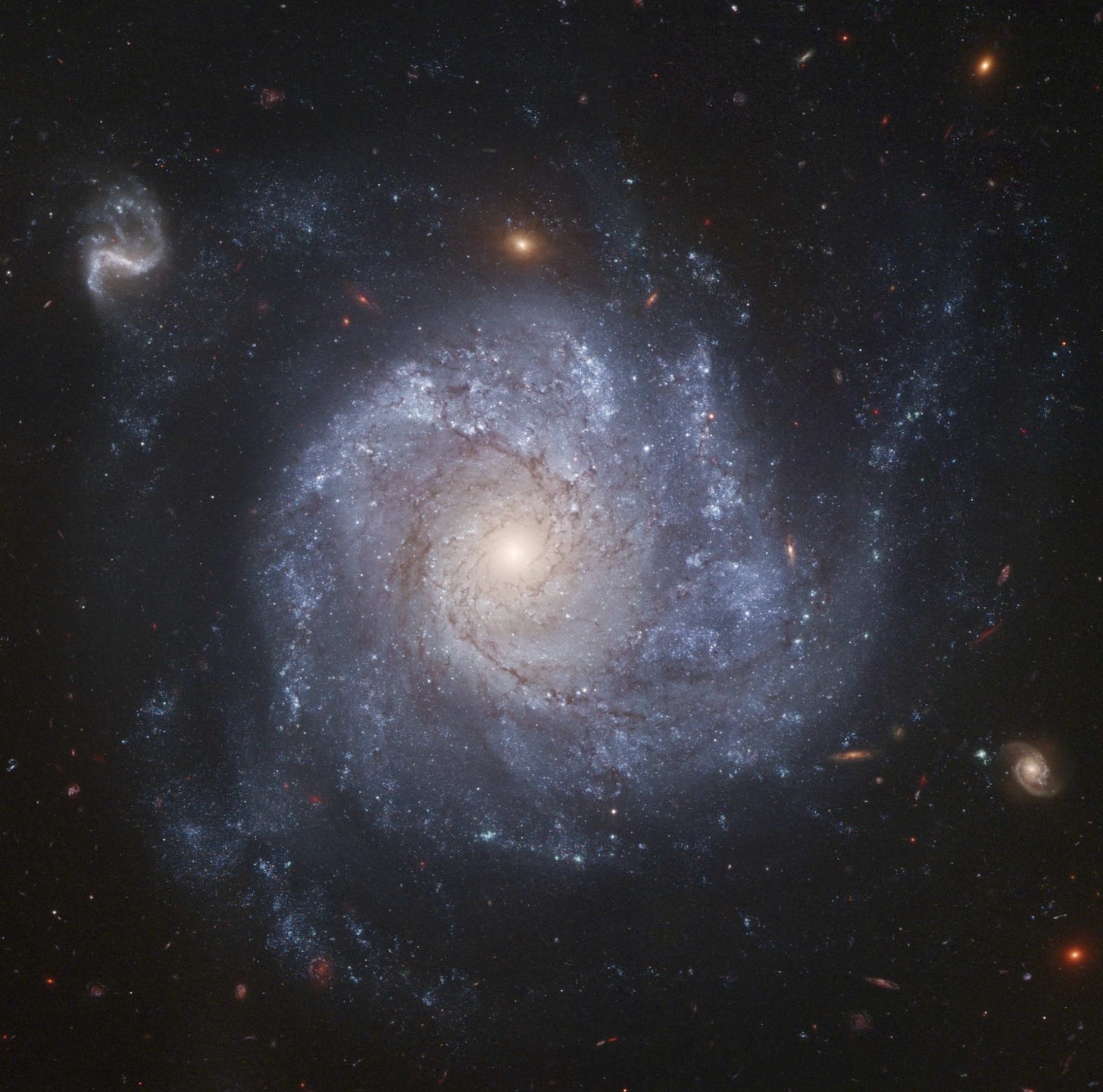 A spiral galaxy with lots of stars and other tiny galaxies around it