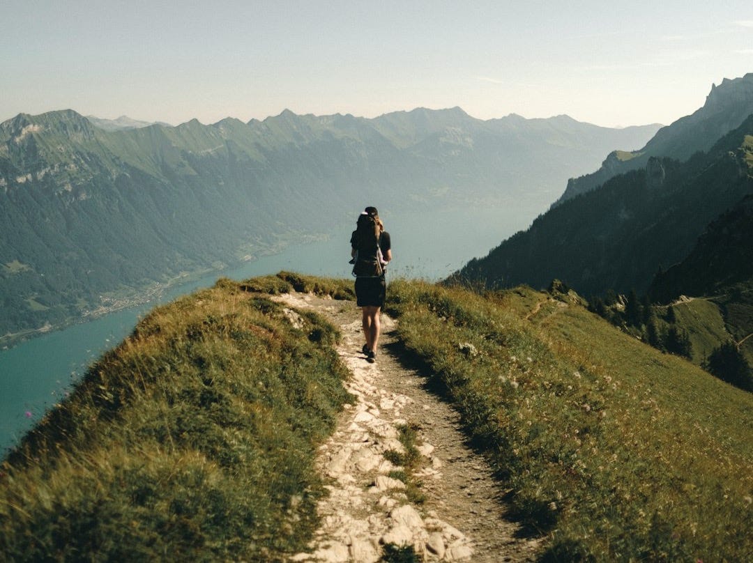person hiking above mountain overlooking river