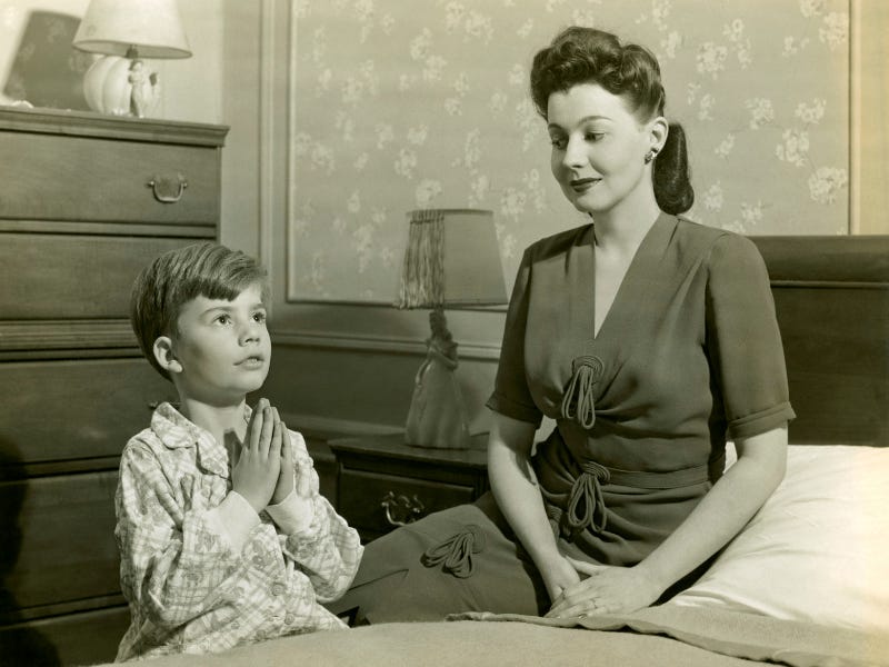 A 1950's-America-style photo of a Mother and son saying prayers before bedtime.