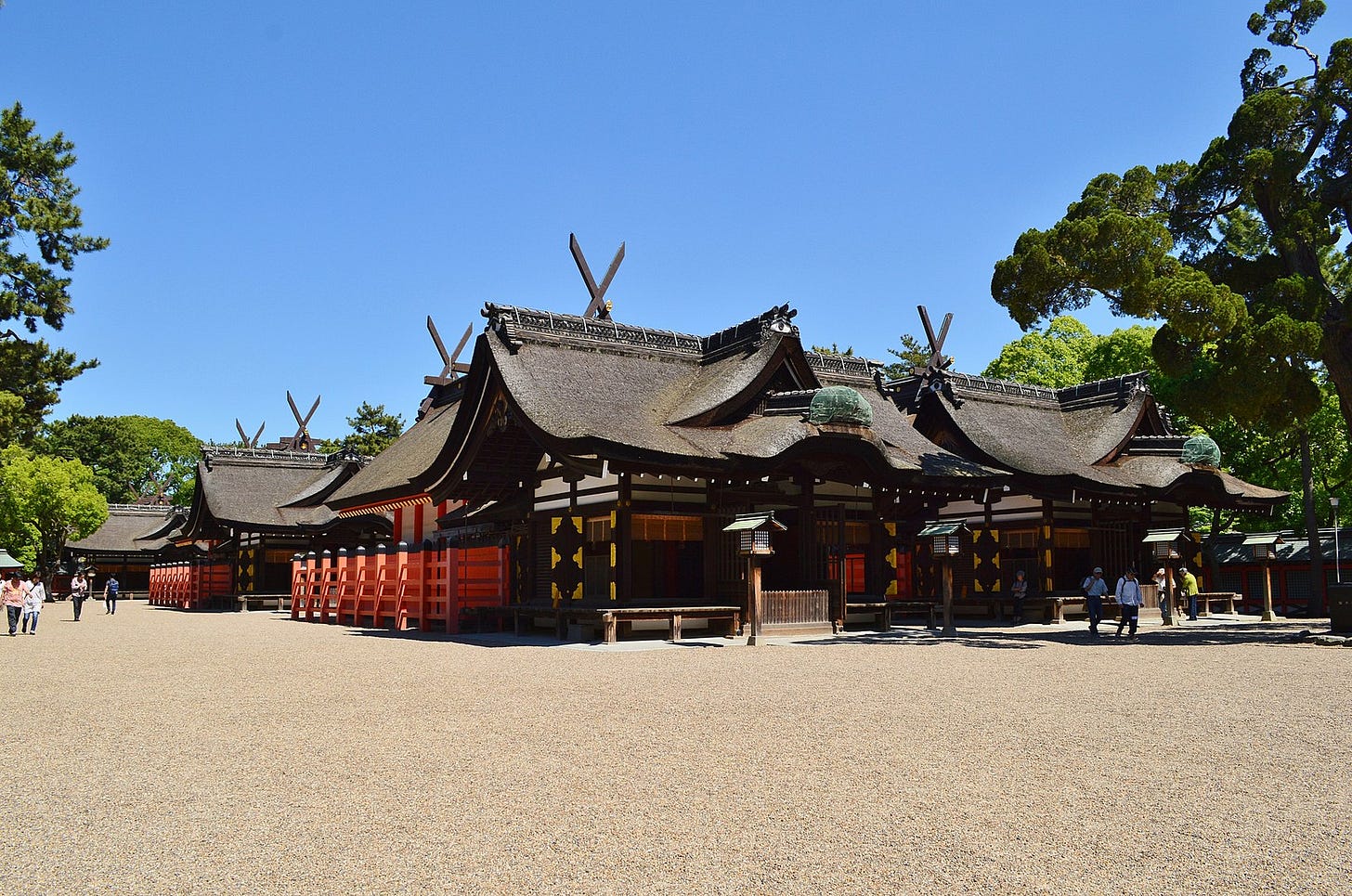 A picture of Sumiyoshi Grand Shrine with the shrine buildings set against a clear blue sky. Sword-like crosses point upwards at the sky from the thatched roofs of the shrine buildings A picture of Sumiyoshi Grand Shrine with the shrine buildings set against a clear blue sky. Sword-like crosses point upwards at the sky from the thatched roofs of the shrine buildings