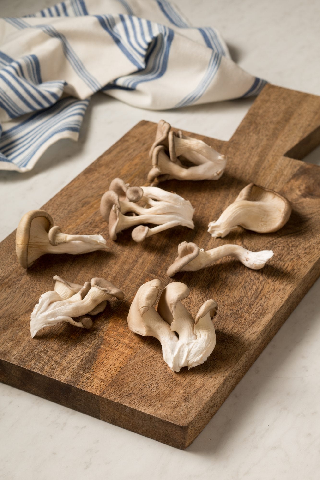 bunch of oyster mushrooms on wood cutting board