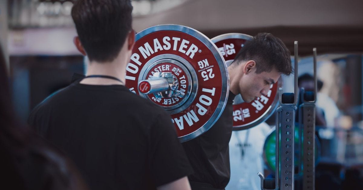 Man lifting weights at an outdoor competition, showcasing strength and focus Man lifting weights at an outdoor competition, showcasing strength and focus