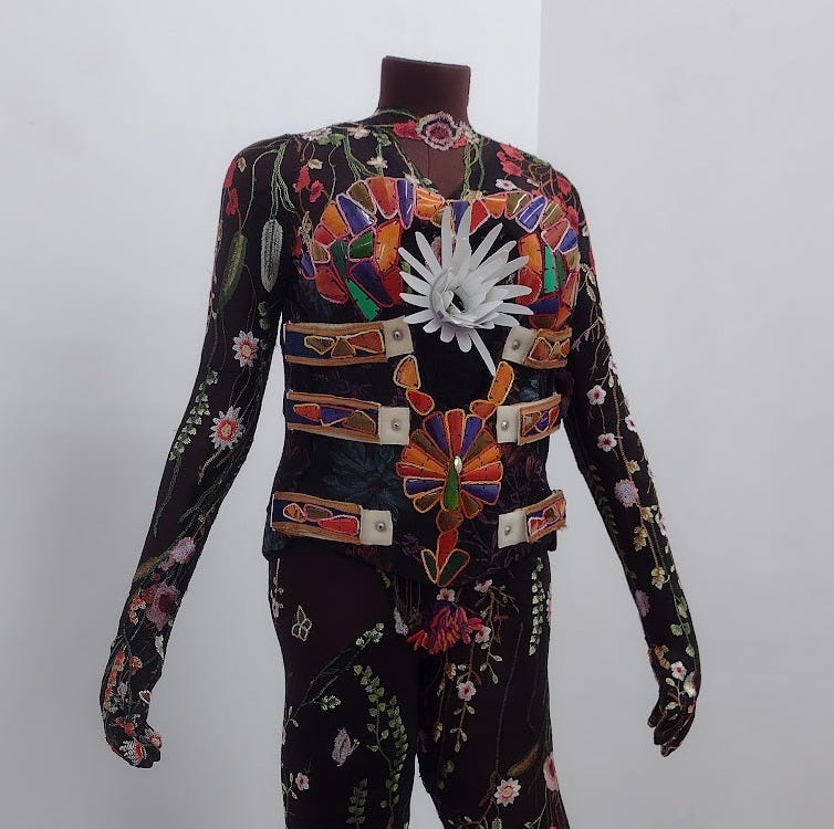 Torso of a headless figure with floral lace skin and a multicolored mosaic back brace