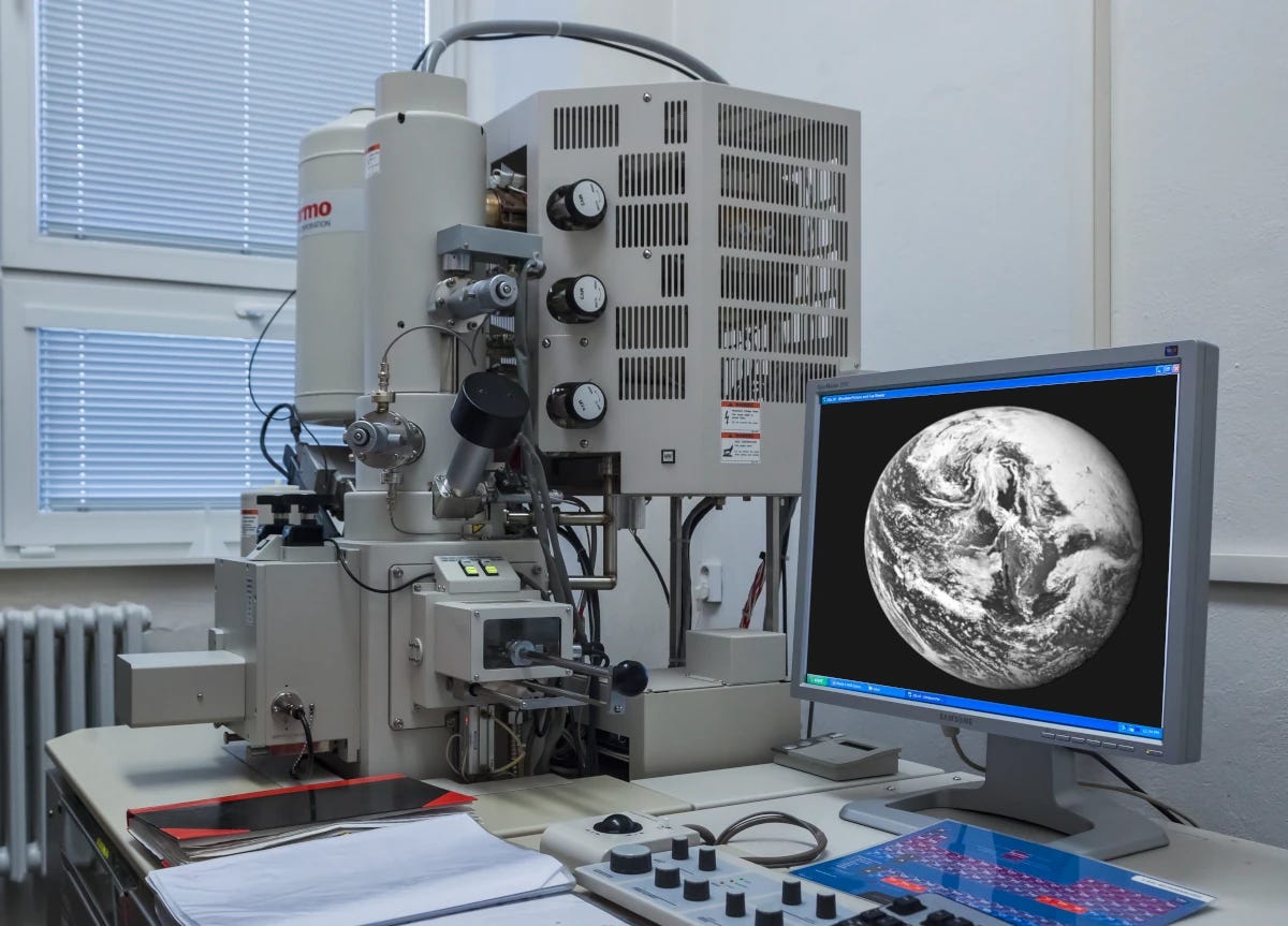 Picture of a scanning electron microscope. Remarkably, the picture on the screen (with a very dark gray background) is a grayscale image of the Earth!