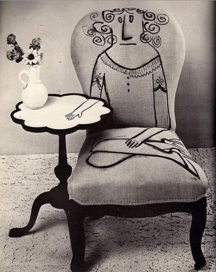 The image showcases a piece of art by Saul Steinberg, as indicated by the post text. It features a vintage chair with a whimsical drawing of a woman's face and upper body on the fabric. The drawing is done in a playful, cartoonish style with exaggerated features and flowing hair. Next to the chair is a small, ornate table with a scalloped edge, holding a vase with flowers. The setting appears to be indoors, with a simple background that emphasizes the artistic chair. The overall composition blends furniture with art, creating a unique and visually engaging piece. The image showcases a piece of art by Saul Steinberg, as indicated by the post text. It features a vintage chair with a whimsical drawing of a woman's face and upper body on the fabric. The drawing is done in a playful, cartoonish style with exaggerated features and flowing hair. Next to the chair is a small, ornate table with a scalloped edge, holding a vase with flowers. The setting appears to be indoors, with a simple background that emphasizes the artistic chair. The overall composition blends furniture with art, creating a unique and visually engaging piece.