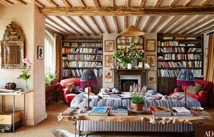 This may contain: a living room filled with furniture and bookshelves next to a fire place in front of a fireplace