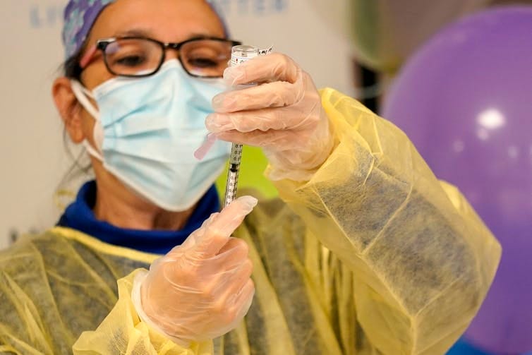 A nurse draws a dose of coronavirus vaccine into a syringe. A nurse draws a dose of coronavirus vaccine into a syringe.