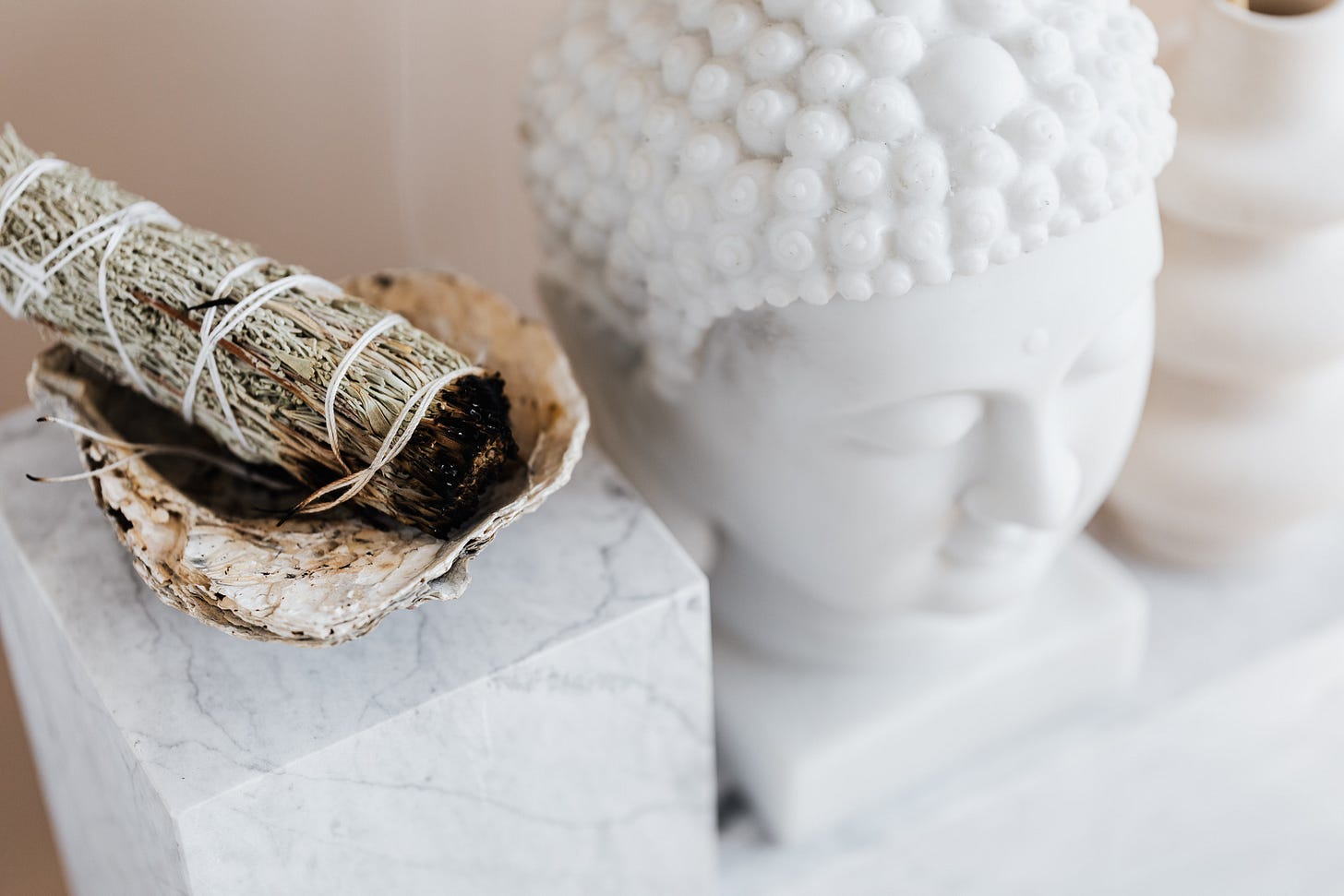 Sage smudge stick in bowl on marble shelf near Buddha head Sage smudge stick in bowl on marble shelf near Buddha head