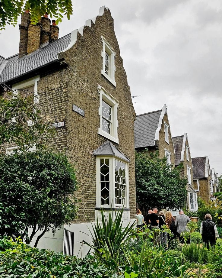 This may contain: people walking in front of a brick building with many windows and plants on the lawn