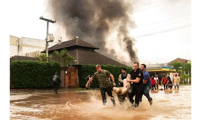 Residents and a policeman carry the body of a victim after an explosion at a petrol station in Porto Alegre. Residents and a policeman carry the body of a victim after an explosion at a petrol station in Porto Alegre.