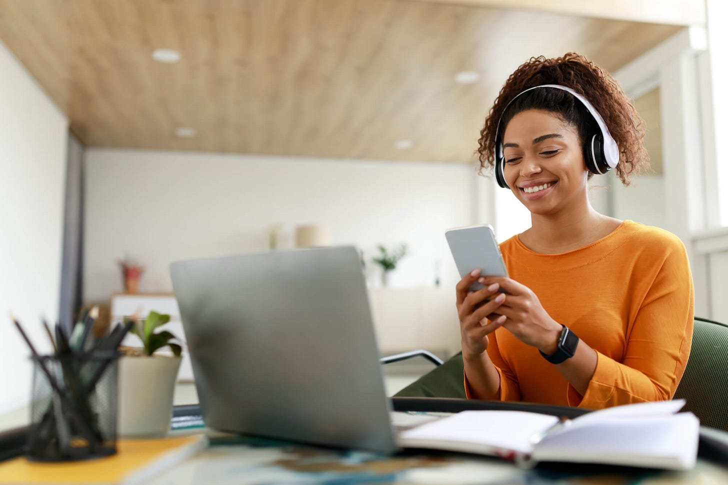A young woman smilin, looking at phone at work
