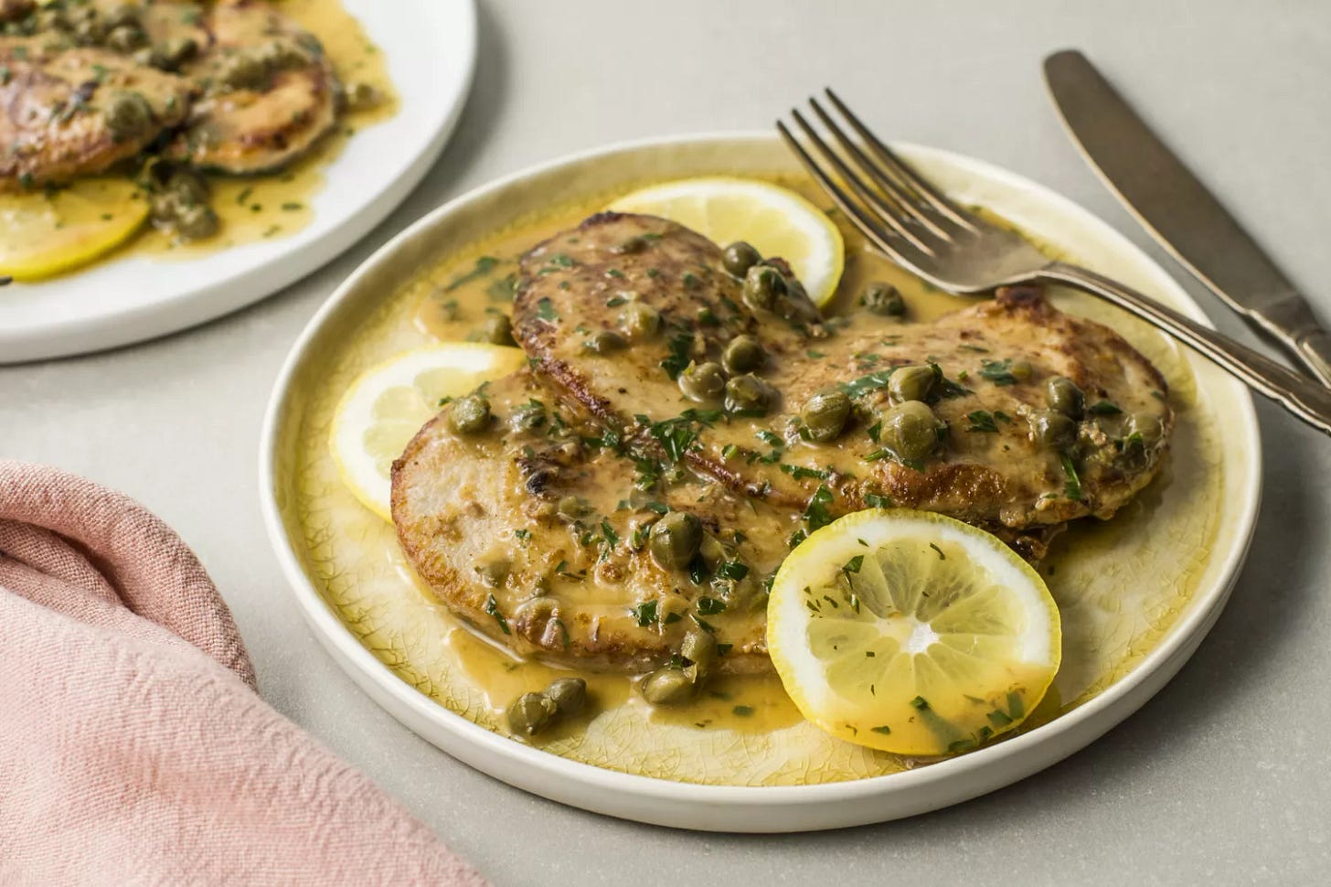 Classic veal piccata with capers and lemon slices on a dinner plate